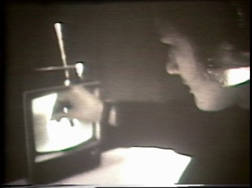 Still from Sequence 18 of Idea Demonstrations. Mike Parr attempts to erase the image of his eyes from his live video image.